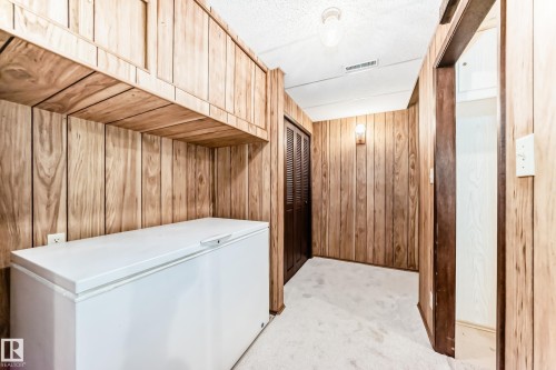 Wood-paneled room featuring built-in overhead cabinetry, ceiling lighting, and wall-mounted sconce - 12022 62 Street, Edmonton, AB 