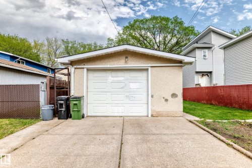 Detached garage featuring a paneled overhead door, stucco exterior finish, and a concrete driveway - 12022 62 Street, Edmonton, AB 