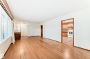 Expansive room featuring wood-finish flooring, white walls, and a large multi-pane window with white trim - 12022 62 Street, Edmonton, AB 