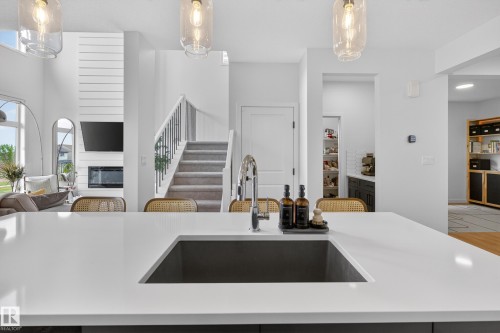 Kitchen island with a dark gray undermount sink, a stainless steel faucet, and a light-toned countertop - 17023 45 Street, Edmonton, AB 