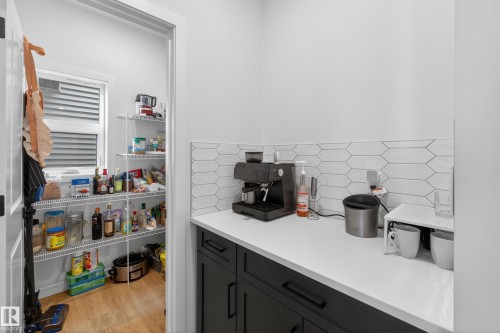 Kitchenette featuring dark-toned base cabinetry, light-toned countertop, and a white picket tile backsplash - 17023 45 Street, Edmonton, AB 