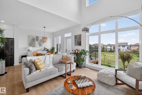 Open-concept living area with wood-finish flooring, soaring ceilings, and expansive windows - 17023 45 Street, Edmonton, AB 