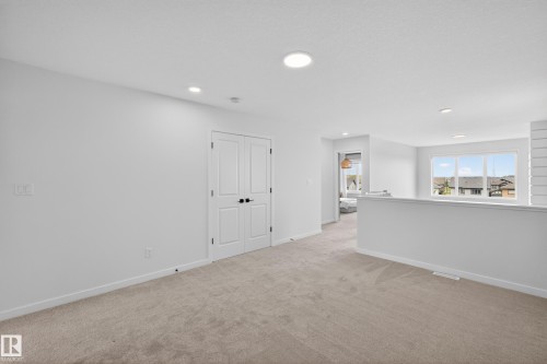 Carpeted open-concept area featuring white walls, recessed lighting, and a partial wall with white trim - 17023 45 Street, Edmonton, AB 
