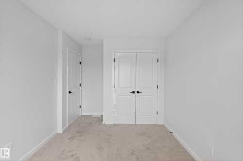 Neutral tone walls with white trim, carpeting, and matte black door hardware - 17023 45 Street, Edmonton, AB 