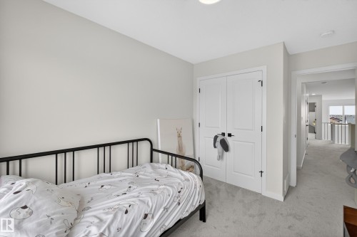 Carpeted bedroom featuring neutral wall tones, a built-in closet with double doors and matte black hardware, and a ceiling-mounted light fixture - 17023 45 Street, Edmonton, AB 