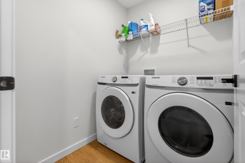 Dedicated laundry area featuring a front-load washer and dryer, wood-finish flooring, and a wall-mounted wire shelving system - 17023 45 Street, Edmonton, AB 
