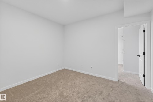 Spacious room featuring neutral carpeting, white baseboards, and bright white walls - 17023 45 Street, Edmonton, AB 