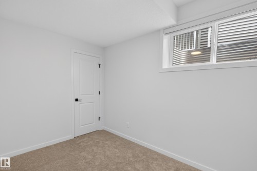 Bedroom featuring soft carpet flooring and a white two-panel door with matte black hardware - 17023 45 Street, Edmonton, AB 