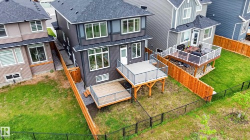 Rear exterior featuring charcoal gray siding with white trim, a large upper deck with dark gray railings, and a lower wooden patio area - 17023 45 Street, Edmonton, AB 