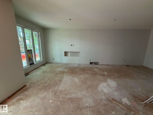 Spacious interior room featuring a large window array, recessed wall niche, and neutral wall finishes - 10985 130 Street, Edmonton, AB 