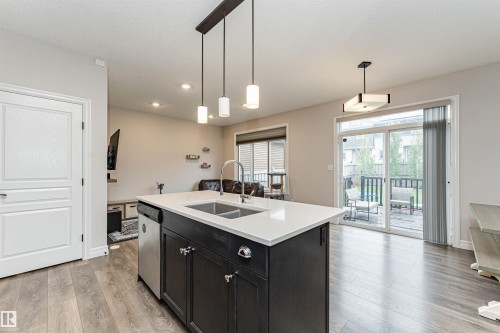 Kitchen island with a double basin sink, stainless steel dishwasher, and pendant lighting - 8744 223 Street Nw, Edmonton, AB 