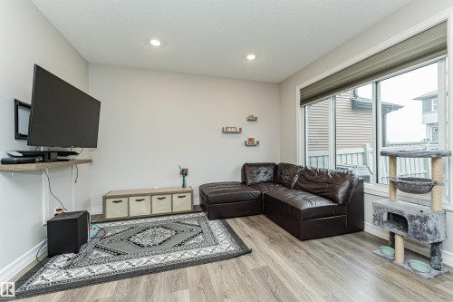 Living area featuring wood-finish flooring and light gray wall paint, with large windows. - 8744 223 Street Nw, Edmonton, AB 