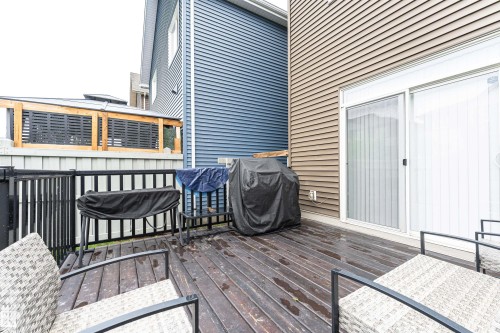 Exterior deck featuring wood-finish flooring, black metal railings, and a sliding glass door - 8744 223 Street Nw, Edmonton, AB 