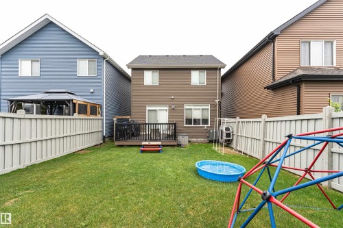 Fenced backyard featuring a manicured lawn and a private wood deck with sliding door access - 8744 223 Street Nw, Edmonton, AB 