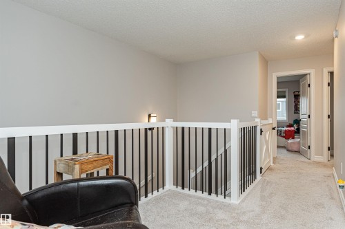 Upper-level landing & bonus area, featuring light gray wall paint and textured carpet flooring - 8744 223 Street Nw, Edmonton, AB 