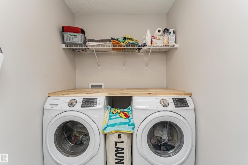 Upstairs is a Dedicated laundry area featuring a wood-finish countertop, dual appliance spaces, and an upper wire shelf for storage - 8744 223 Street Nw, Edmonton, AB 