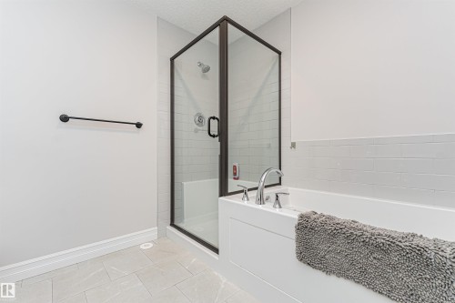 Contemporary bathroom featuring a frameless glass shower enclosure with dark bronze trim, white subway tile shower surround, chrome shower fixtures, and a built-in shower bench - 8744 223 Street Nw, Edmonton, AB 