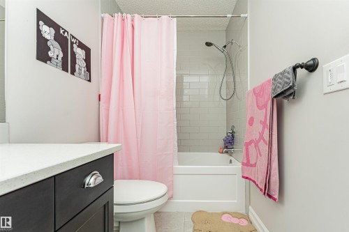 Bathroom featuring a dark wood vanity with white countertop, subway tile shower surround, and a white bathtub - 8744 223 Street Nw, Edmonton, AB 