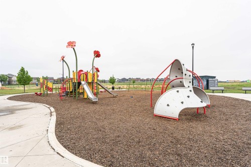 Community playground featuring a climbing structure, slides, and wood chip surfacing - 8744 223 Street Nw, Edmonton, AB 