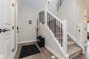 Foyer featuring wood-finish flooring, white trim, and a staircase with carpeted treads and black metal spindles - 8744 223 Street Nw, Edmonton, AB 