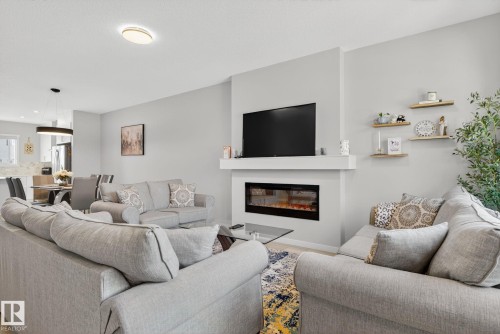 Living area featuring a built-in linear electric fireplace with a mantle, recessed wall-mounted television, and light-colored walls - 1213 16A Street, Edmonton, AB 