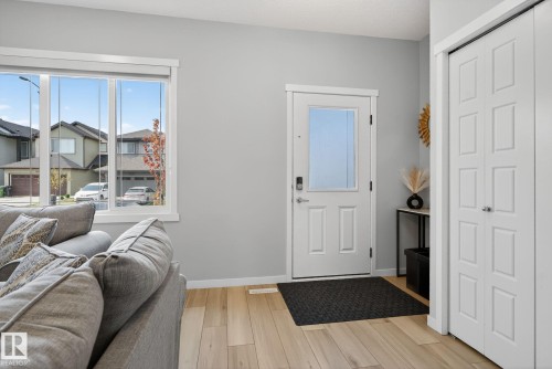 Entryway featuring light wood-finish flooring, a white paneled door with frosted glass, and white bi-fold closet doors - 1213 16A Street, Edmonton, AB 