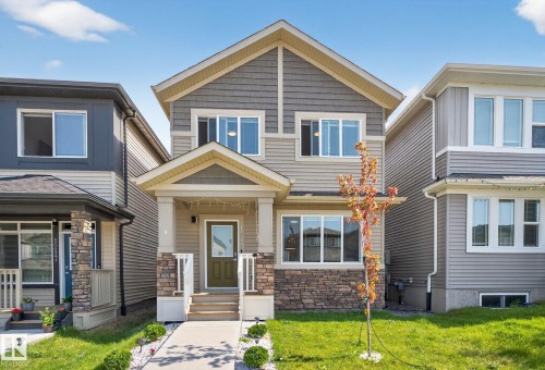Two-story property featuring a covered front porch with stone accents, horizontal siding, shake siding, and multiple windows - 1213 16A Street, Edmonton, AB 