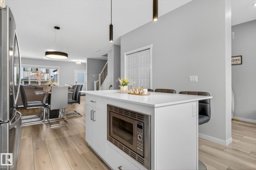 Contemporary kitchen island with a built-in stainless steel microwave, white cabinetry, and a light-toned countertop - 1213 16A Street, Edmonton, AB 