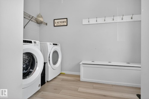 Dedicated laundry area featuring light wood-finish flooring, a wall-mounted wire shelving unit, and a six-hook coat rack - 1213 16A Street, Edmonton, AB 