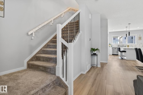 Carpeted staircase with white newel posts and black metal spindles - 1213 16A Street, Edmonton, AB 