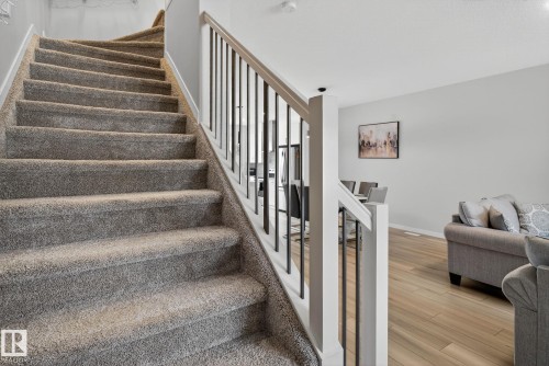 Carpeted staircase with white newel posts and black metal balusters - 1213 16A Street, Edmonton, AB 