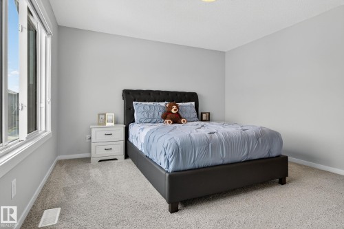 Carpeted room featuring light gray walls, a window with white trim, and a white two-drawer nightstand - 1213 16A Street, Edmonton, AB 