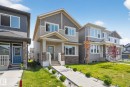 Contemporary-style residence featuring a prominent front gable, stone veneer accents, multi-pane windows, a covered entry porch, and a concrete pathway with landscape lighting - 1213 16A Street, Edmonton, AB 