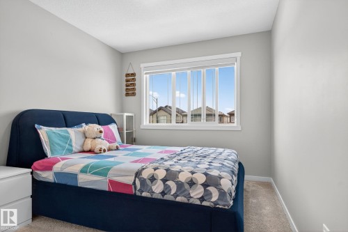 Bright bedroom featuring a large window with white trim, light gray walls, and soft carpeting - 1213 16A Street, Edmonton, AB 