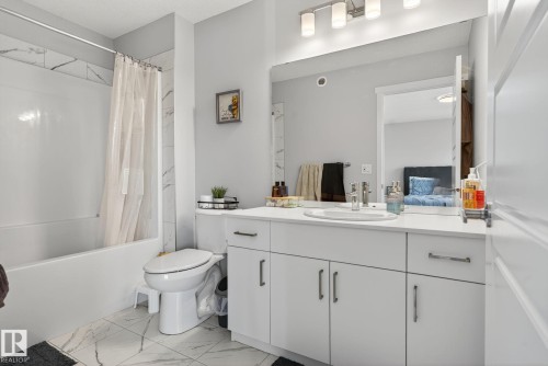 Bathroom featuring a white vanity with an integrated sink, polished chrome fixtures, and a four-light bar fixture - 1213 16A Street, Edmonton, AB 