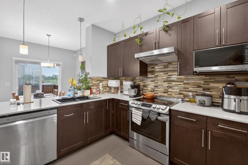 Modern kitchen featuring dark wood cabinetry and contrasting light countertops - 1404 25 Avenue, Edmonton, AB 