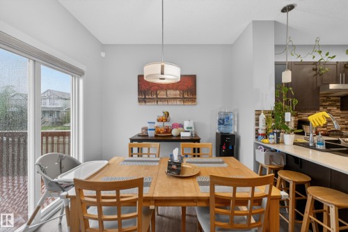Dining area featuring wood-finish flooring, a contemporary drum pendant light, and sliding glass doors opening to a deck - 1404 25 Avenue, Edmonton, AB 