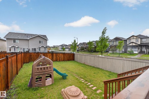 Rear yard featuring a brown privacy fence, a wooden deck with railings, and a stepping stone path - 1404 25 Avenue, Edmonton, AB 