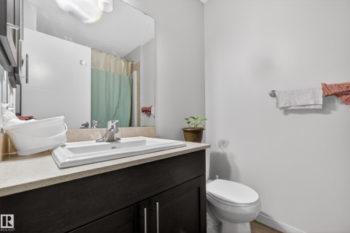 Dark wood-finish vanity with a white rectangular undermount sink, a chrome faucet, and a light-toned countertop - 1404 25 Avenue, Edmonton, AB 