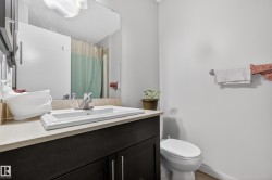 Dark wood-finish vanity with a white rectangular undermount sink, a chrome faucet, and a light-toned countertop - 