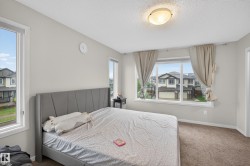 Carpeted bedroom featuring light gray walls and multiple windows, including a large picture window - 