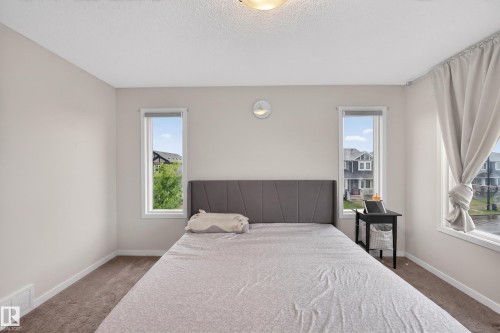 Neutral toned bedroom featuring light grey walls, white trim, and a textured carpet - 1404 25 Avenue, Edmonton, AB 