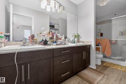Bathroom featuring a double vanity with dark wood-finish cabinetry, light-toned countertop, and dual sinks - 