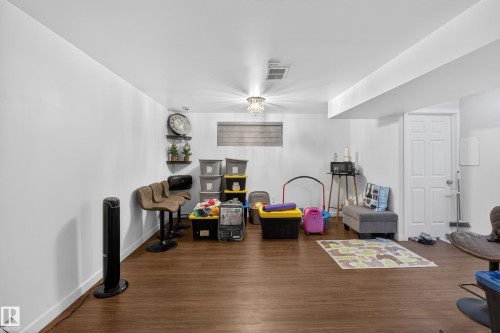 Spacious room featuring wood-finish flooring, white walls, recessed lighting, and a six-panel door - 1404 25 Avenue, Edmonton, AB 
