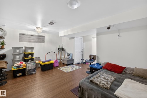 Spacious room featuring wood-finish flooring, recessed lighting, and a white paneled door - 1404 25 Avenue, Edmonton, AB 