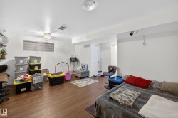 Spacious room featuring wood-finish flooring, recessed lighting, and a white paneled door - 