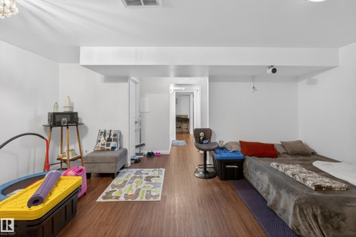 Spacious room featuring wood-finish flooring, white walls, and recessed lighting - 1404 25 Avenue, Edmonton, AB 