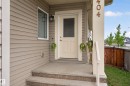 Front entry featuring a cream-colored door with a screen, composite siding, and a concrete porch with aggregate-finish steps - 1404 25 Avenue, Edmonton, AB 