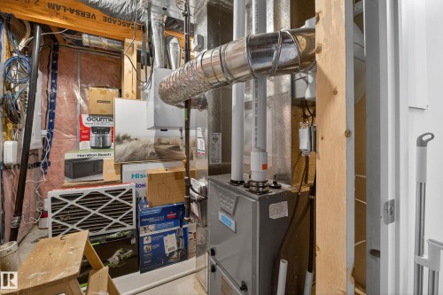 Mechanical room featuring a furnace unit, water heater, and exposed ductwork - 1404 25 Avenue, Edmonton, AB 