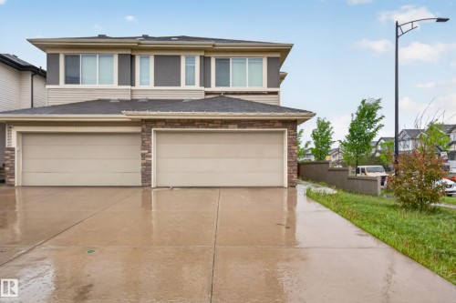 Contemporary property exterior featuring a two-car garage with individual doors, a concrete driveway, and a stone accent facade - 1404 25 Avenue, Edmonton, AB 